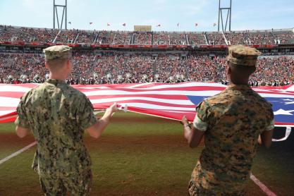 US Service men holding the edge of a flag that is being spread across the whole Scot Stadium field during a game
