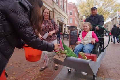 Child in a wheelchair trick or treating on the downtown Charlottesville mall