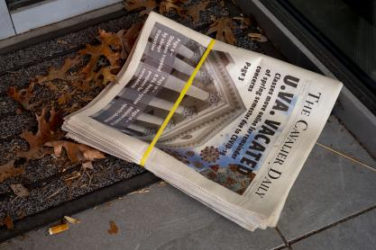 Stack of Newspapers sitting on a porch in on a welcome mat and leaves