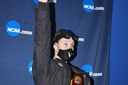 Paige Madden raising her arm while holding the NCAA trophy