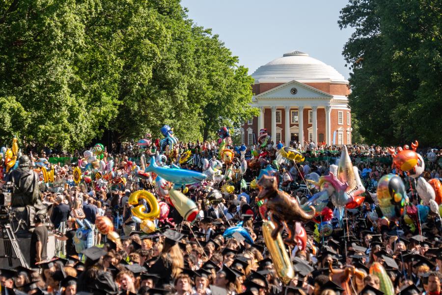 A crown of UVA graduates during Final Exercises on the Lawn holding graduation ballons