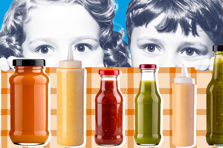 Two children looking over the edge of a table at a variety of condiments