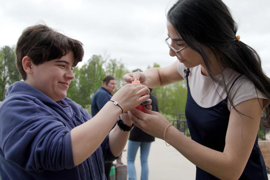 UVA alumna Ludi Avagyan helping a kid open a bottle of paint