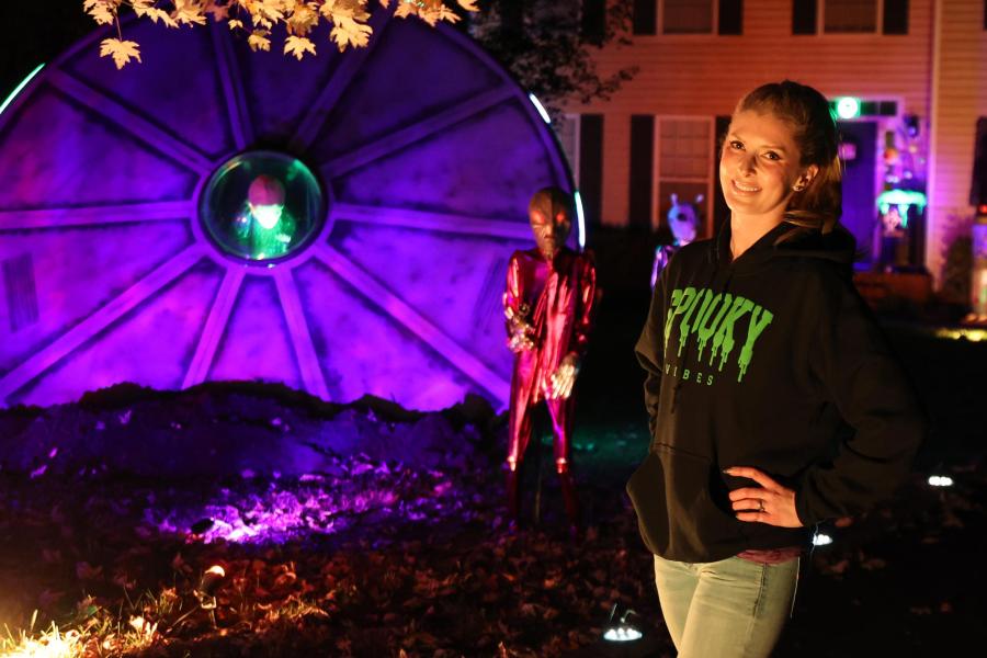 Garnett Mingledorff posing in her front yard in front of a giant light up UFO she constructed.