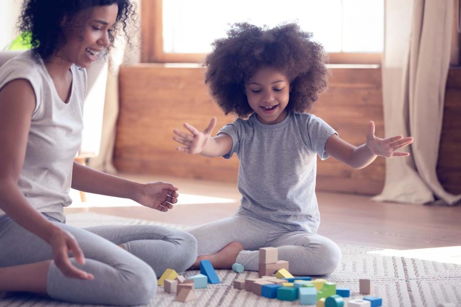 a mother and child playing with blocks on a rug.