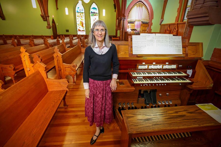 Barbara Moore standing in the UVA Chapel next to the church organ