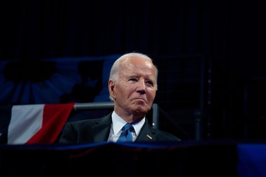 Former President Joe Biden sitting on stage at a conference
