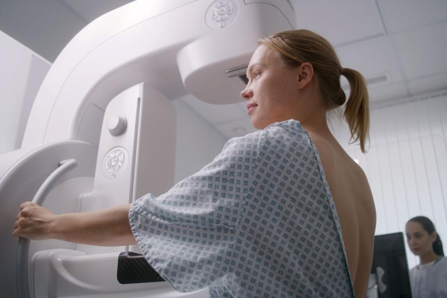 Portrait of a woman wearing patient gown and undergoing her mammogram test.