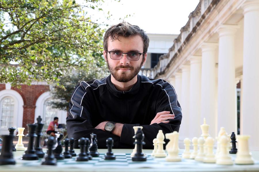 Fourth-year student Jason Morefield poses behind his chess pieces 