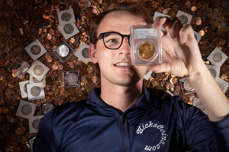 Hunter Hicks examines a graded coin in front of a background of other collector coins