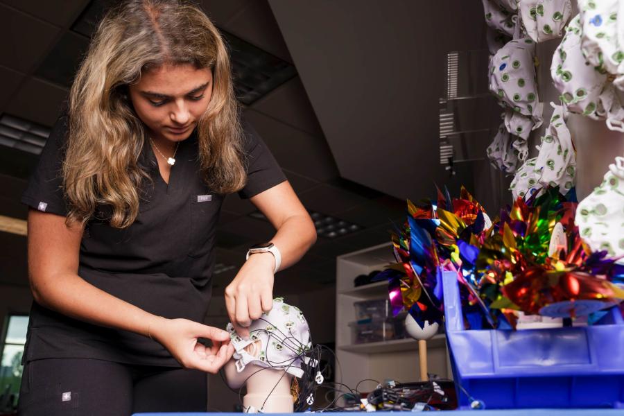 Nora Fotuhi practicing placing a brainwave monitoring cap on a medical mannequin