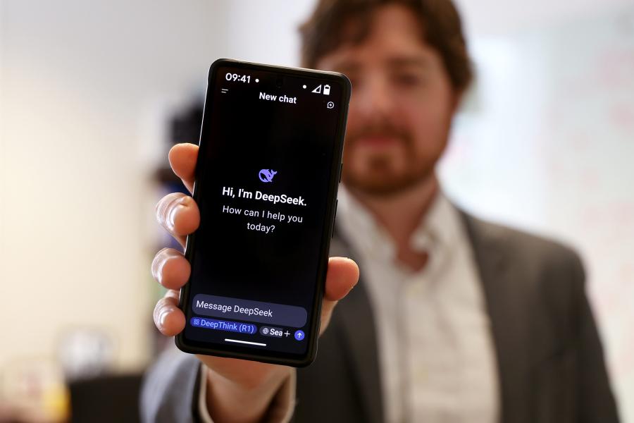 A person holds out a phone with DeepSeek AI displayed on the screen