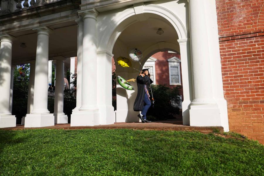 A graduate adjusts their mortarboard as they walk over to the Rotunda to line up for Final Exercises 2025