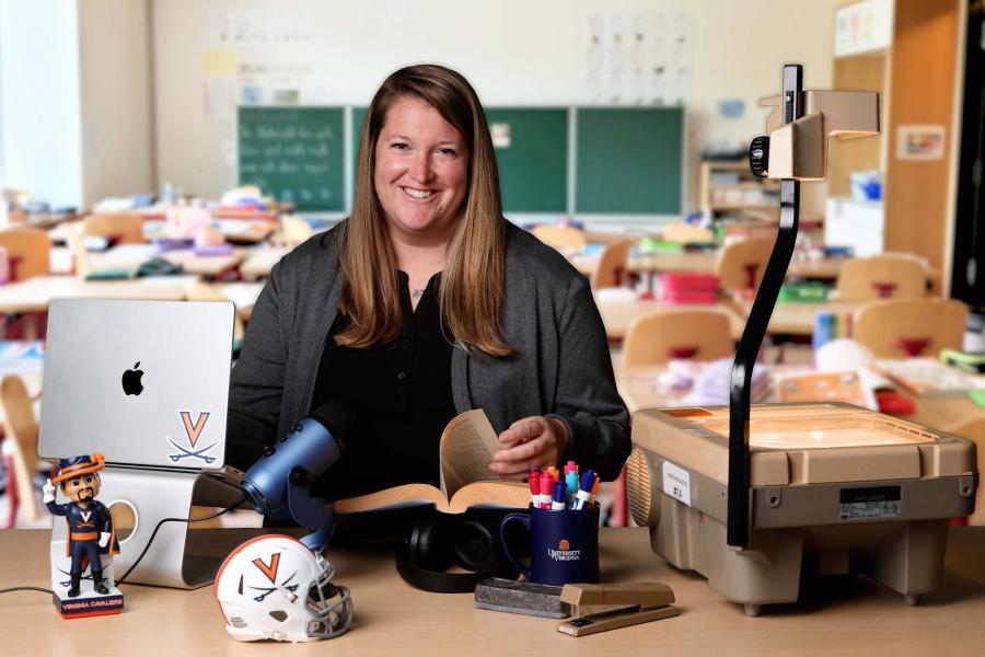 Anne Jewett sitting at her desk with a virtual classroom background
