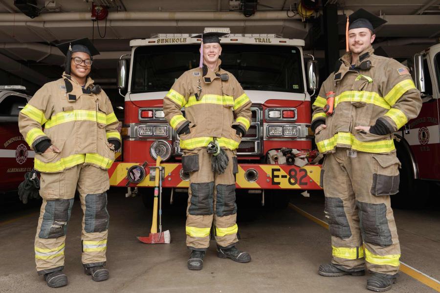 Portrait of UVA Graduate from left Takelia Jones, Kevin Holcombe and Mannix Green in fire fighter uniform.