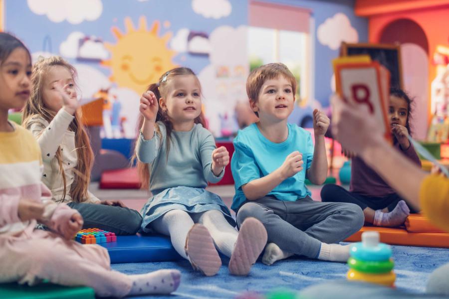 young children participate in a story time activity with their teacher.