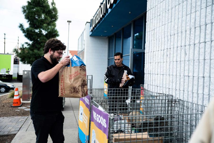 Two Goodwill employees bringing in bags of donations