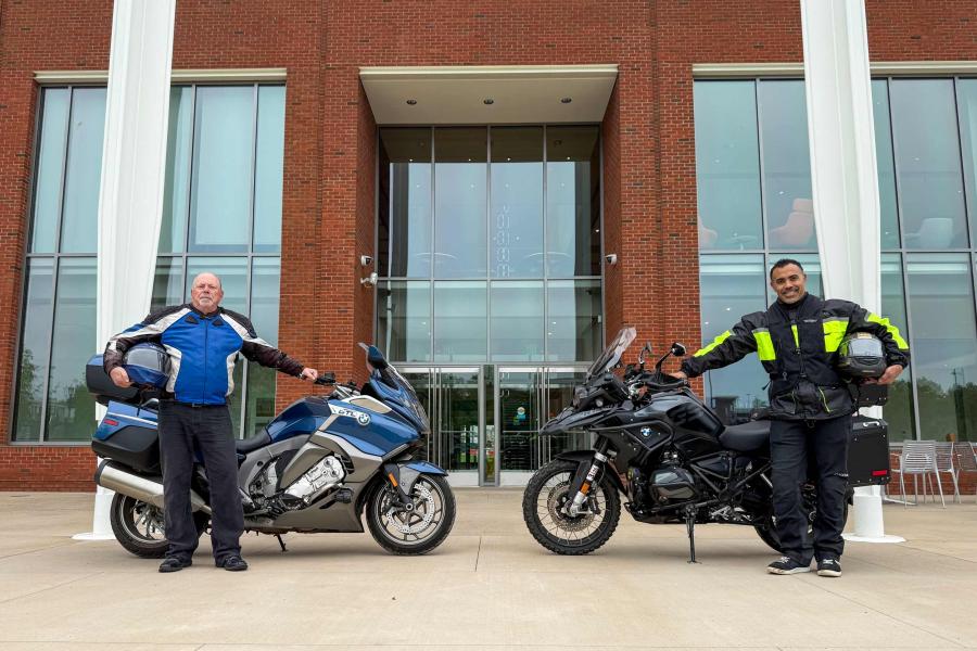 Philip Bourne and Ian Solomon posing next to their motorcycles in front of the UVA School of Data Science