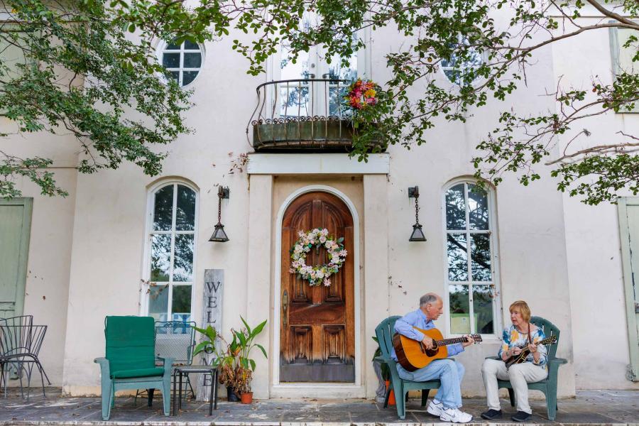 Dr. JoAnn Pinkerton and Alan Pinkerton sit outside the front door of their home playing mandolin and guitar