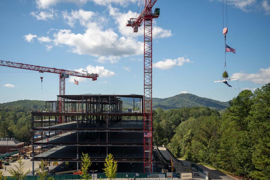 Aerial view of a construction crane operator lifting a steel beam into place during building construction.