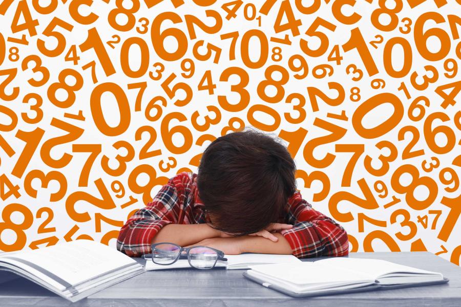 student laying head on desk surrounded by numbers and books