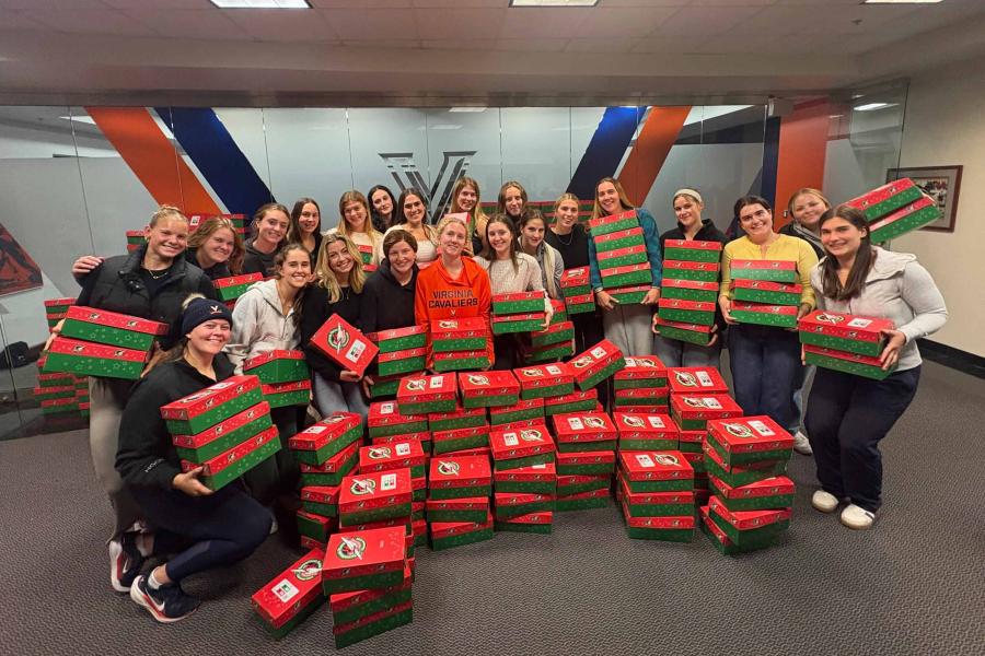 the UVA women's rowing team posing for a photograph behind 133 shoeboxes.