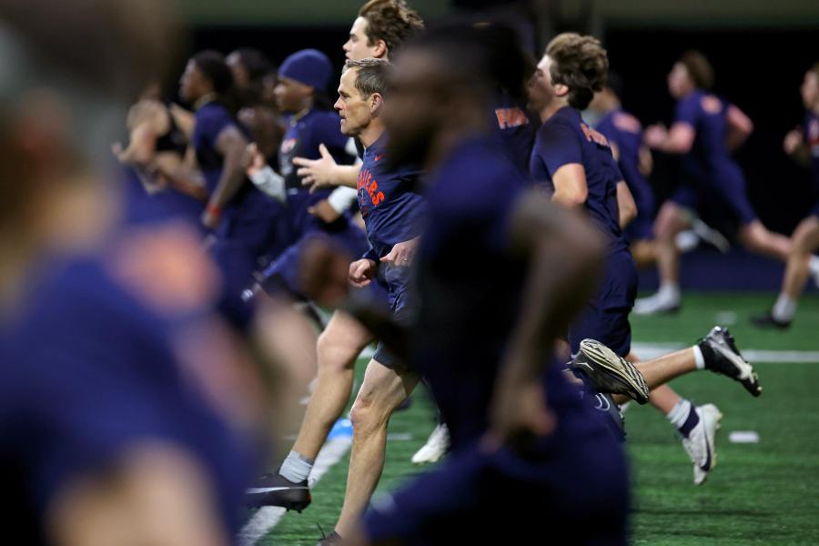 Candid portrait of President Ryan with the UVA football team during a morning workout.