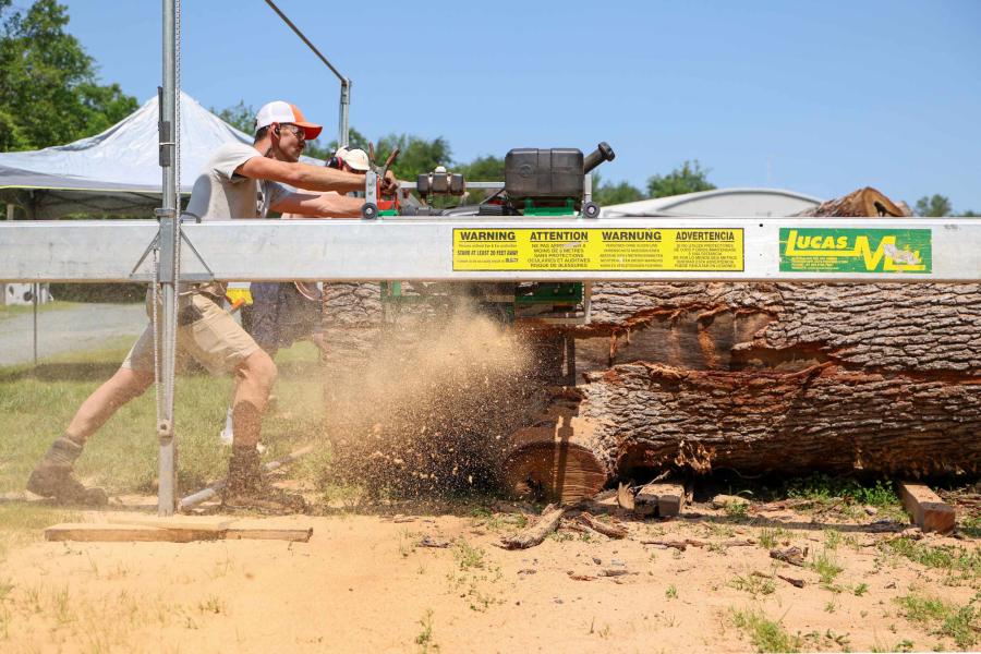 Portrait of Sawyer Wade Cotten guides a 72-inch chainsaw bar through a 48-inch-wide, 11-foot-long white oak log, slicing off a 2 1/2-inch slab