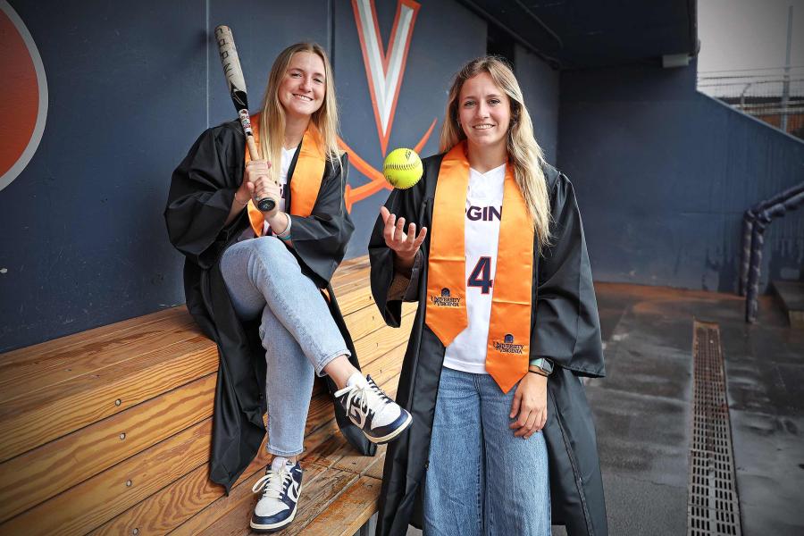Jade Hylton and Eden Bigham standing in a dug out wearing graduation robe