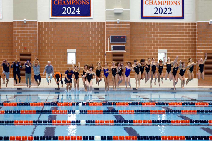 Portrait of Members of the UVA community join the Cavalier women’s swimming and diving team in a celebratory leap into the pool at the Aquatic & Fitness Center.