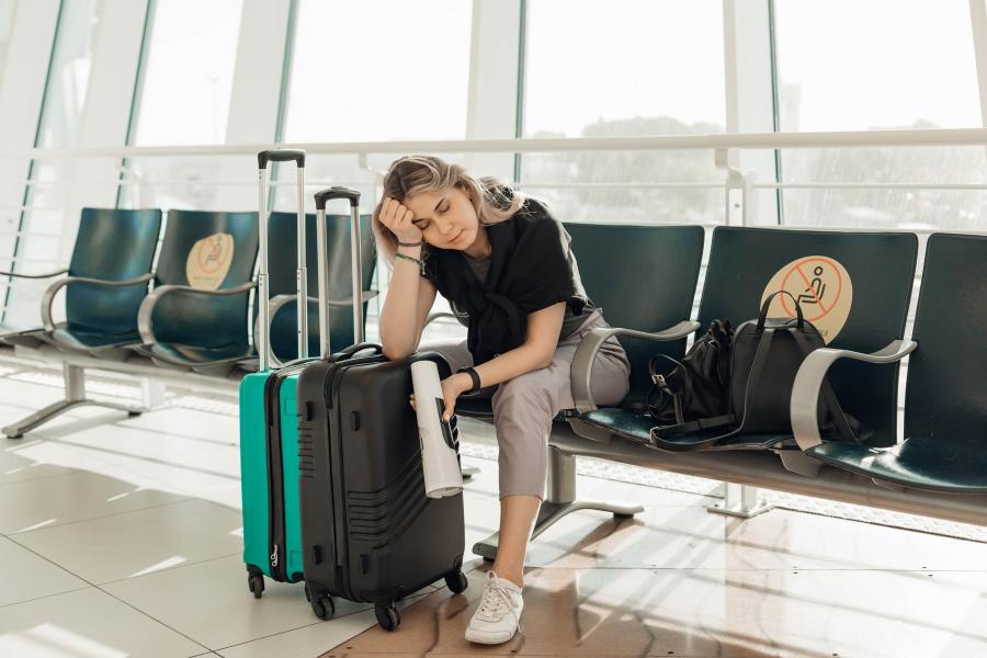 tired person sitting at an airport gate with suitcases