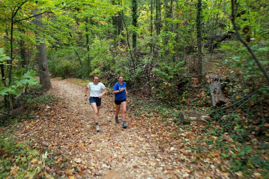 Emily Carder and Sophia Gibby running together on a wooded trail