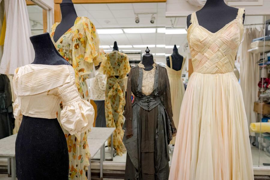 Various dresses hang on mannequin frames