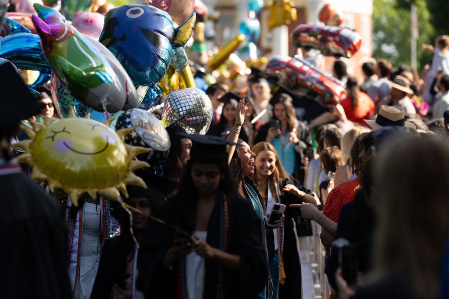 A 2025 graduate pauses in the procession to give a joyful smile and wave to their family