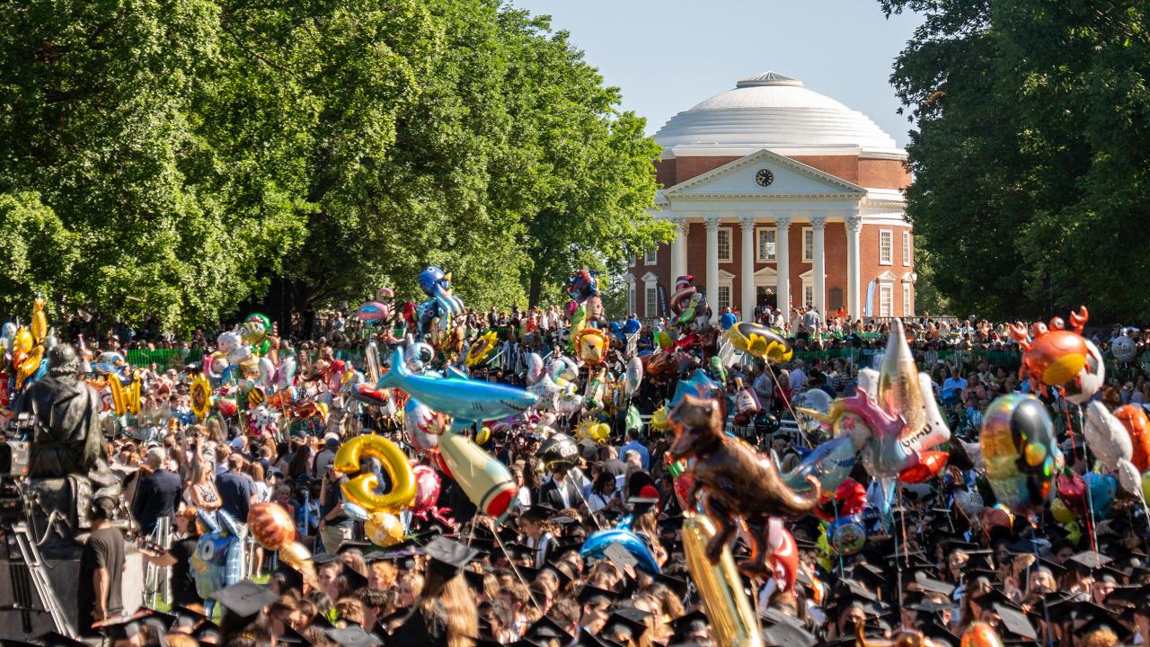 A crown of UVA graduates during Final Exercises on the Lawn holding graduation ballons