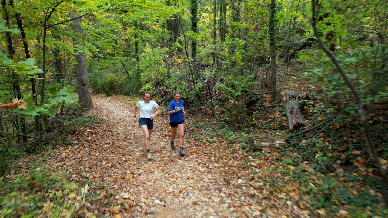 Emily Carder and Sophia Gibby running together on a wooded trail