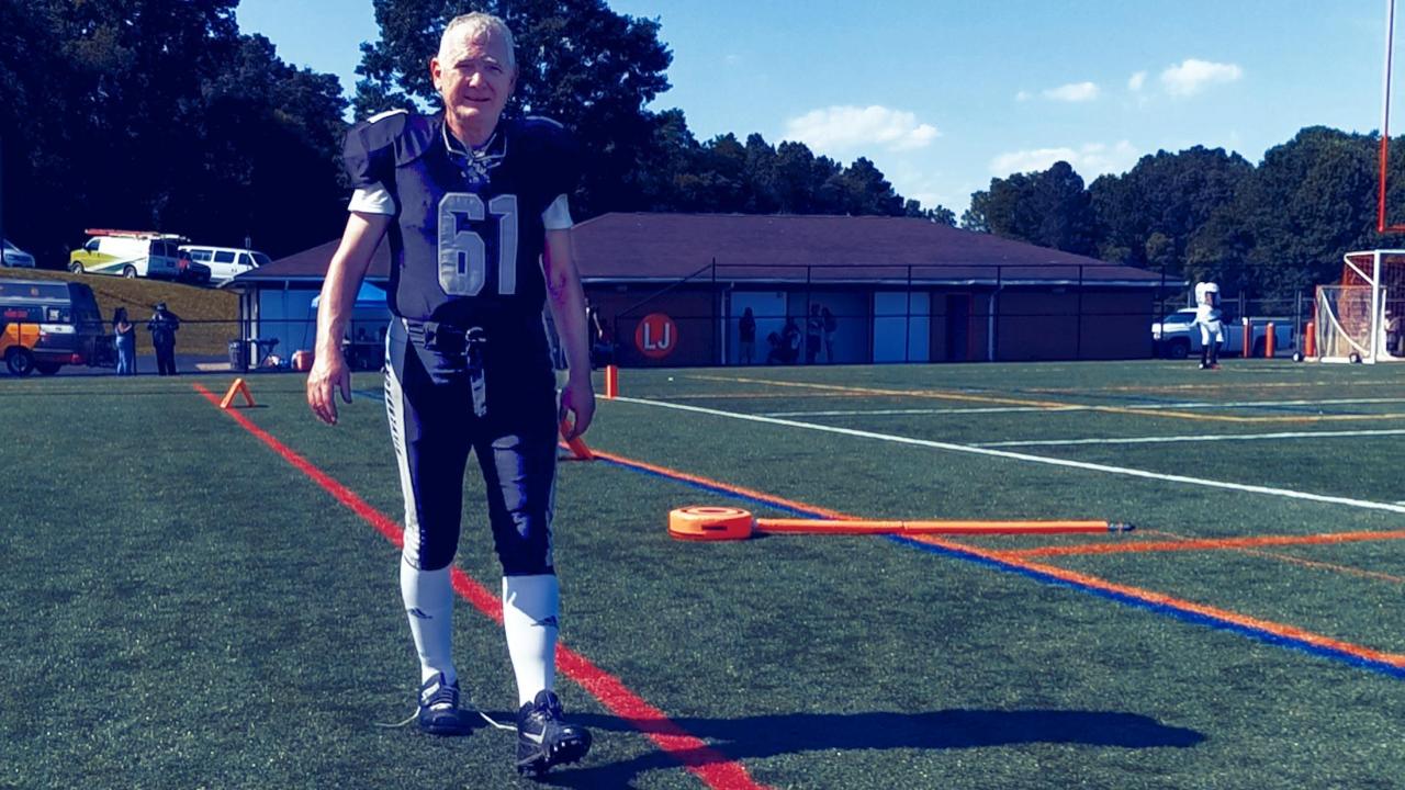 Lynch in a football uniform walks on a football field