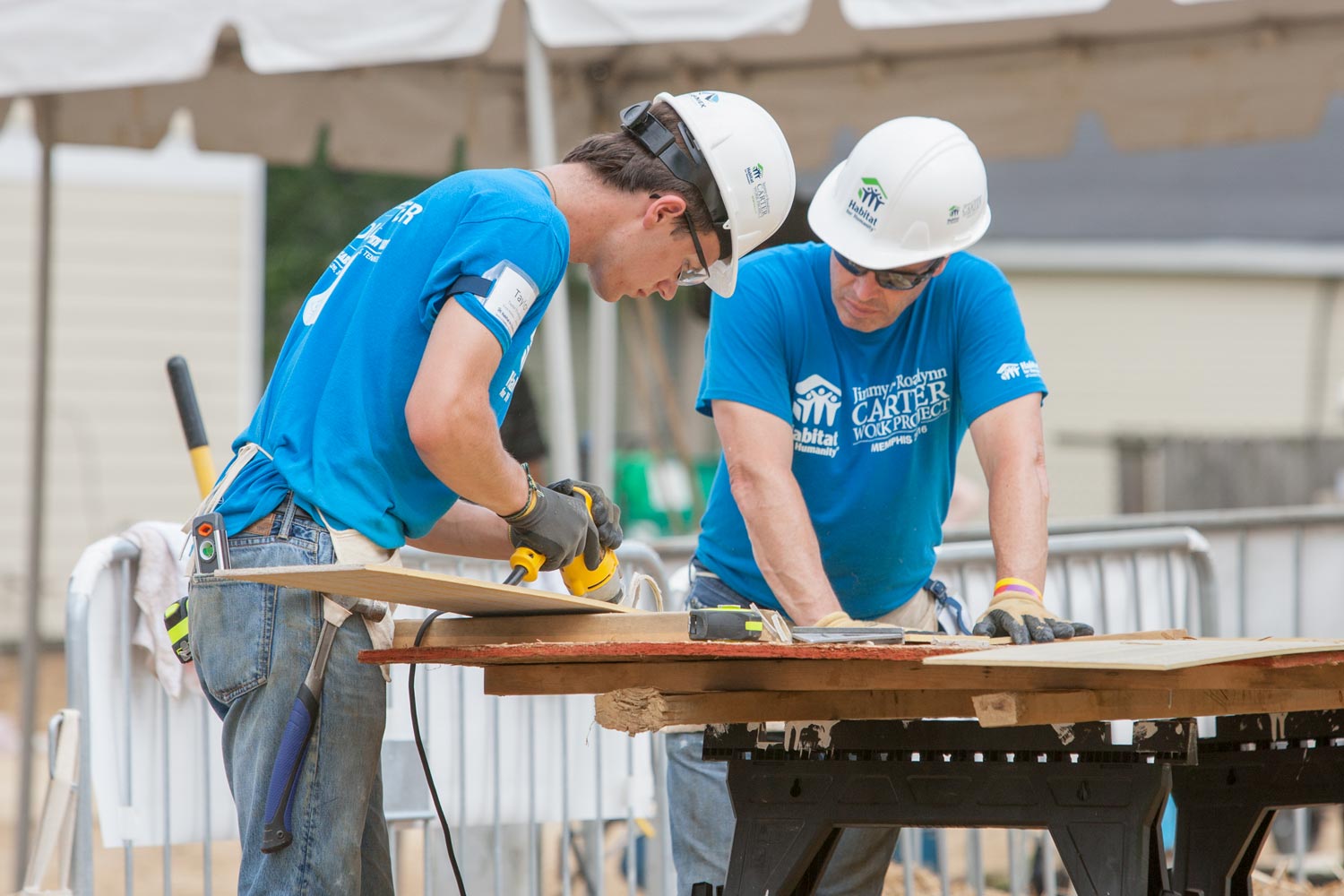 Thompson working with a man to cut a board