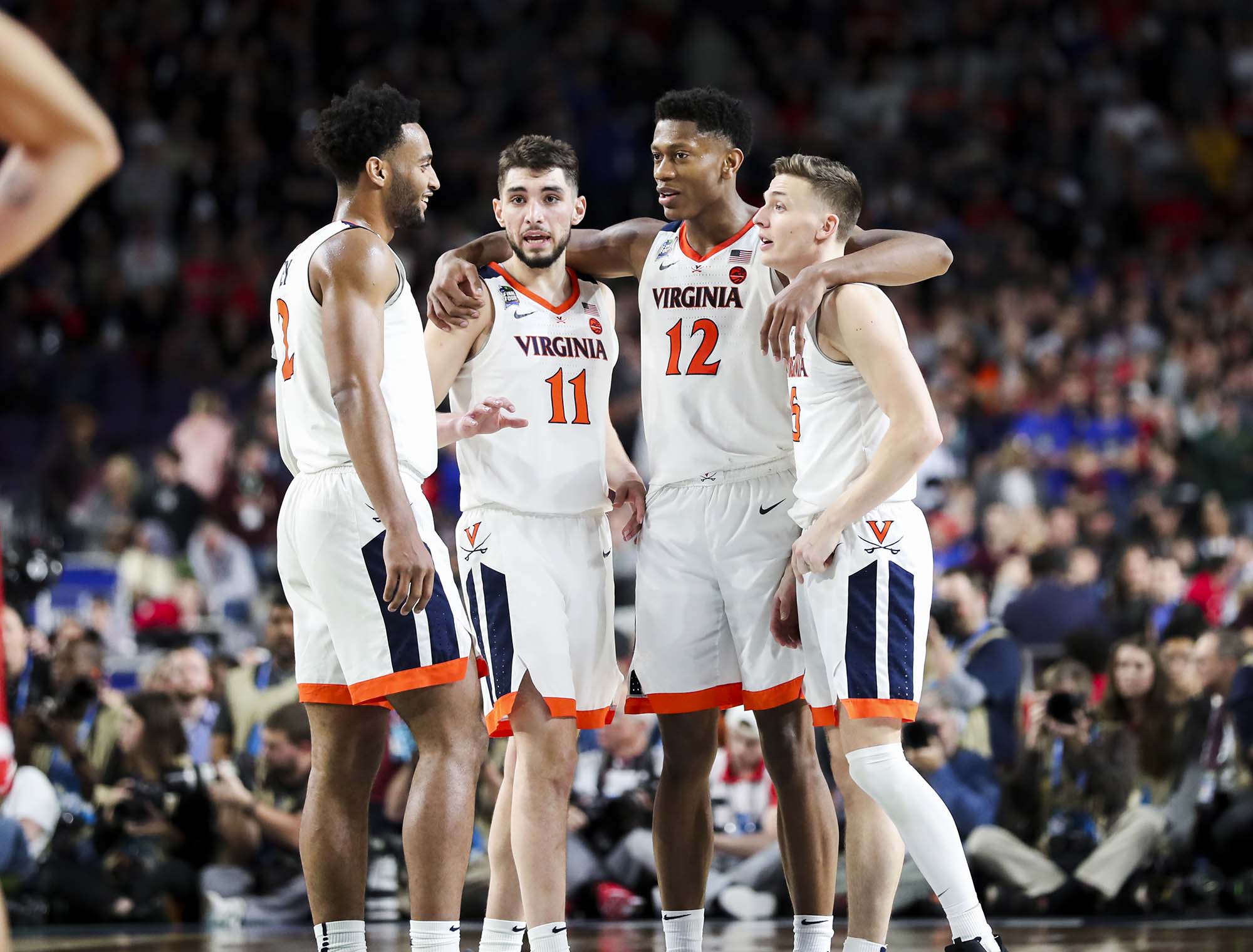 four UVA basketball players wrap arms around each other on the court