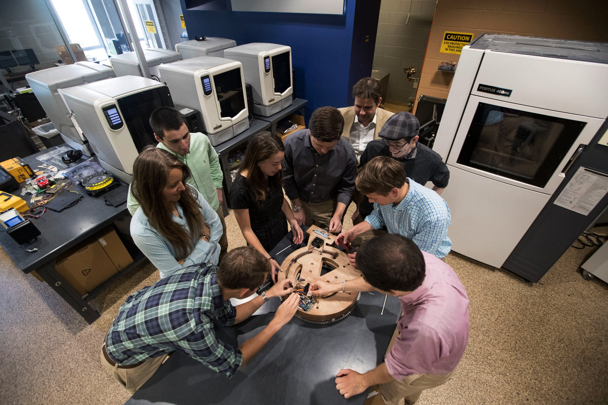 Nine students huddled over a clock