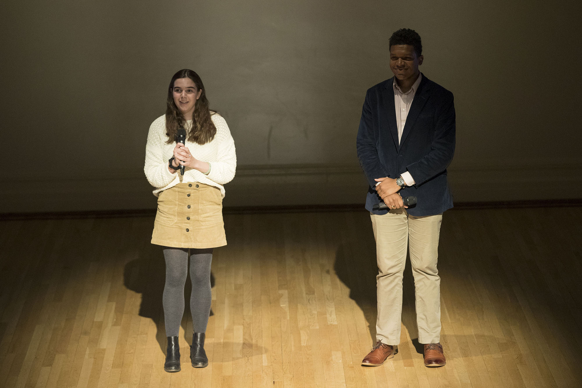 Eleanor Thompson and Ja’Mel Reed stand on stage together.  Eleanor is talking into a microphone