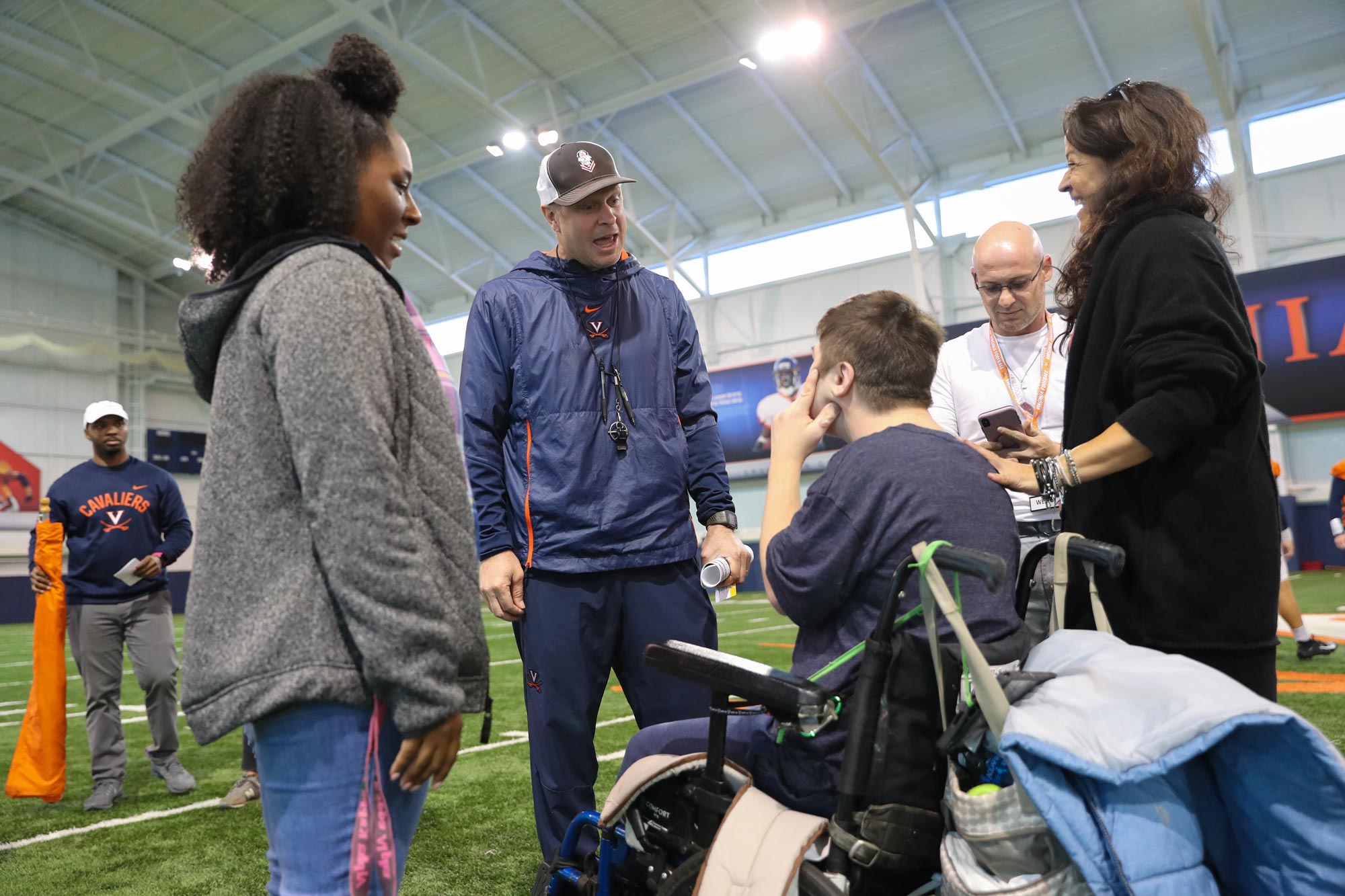 Bronco Mendenhall, speaks to a child and his family on the indoor practice field