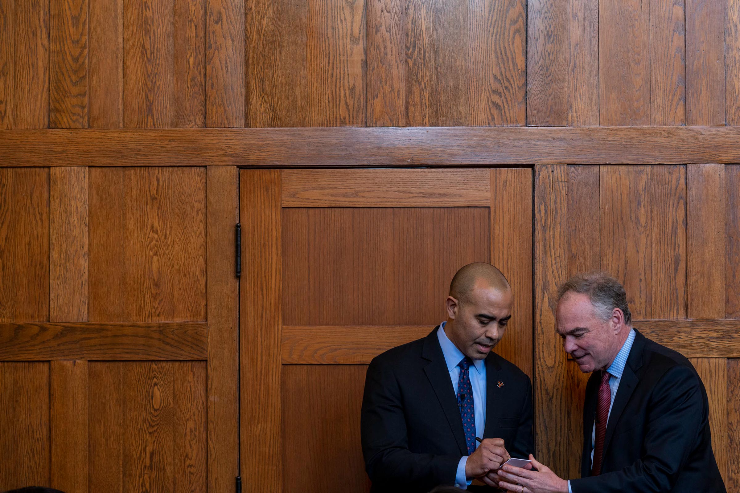 Iam Solomon, left, and Sen. Tim Kaine, right look at at a phone