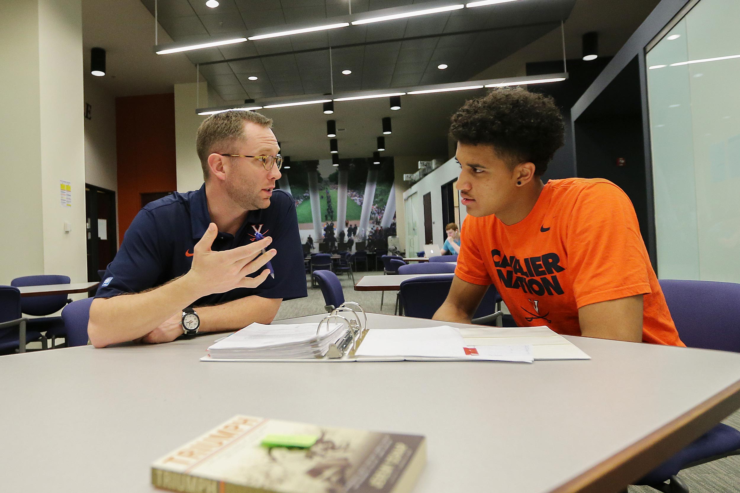 Grams talks with Isaiah Wilkins at a desk