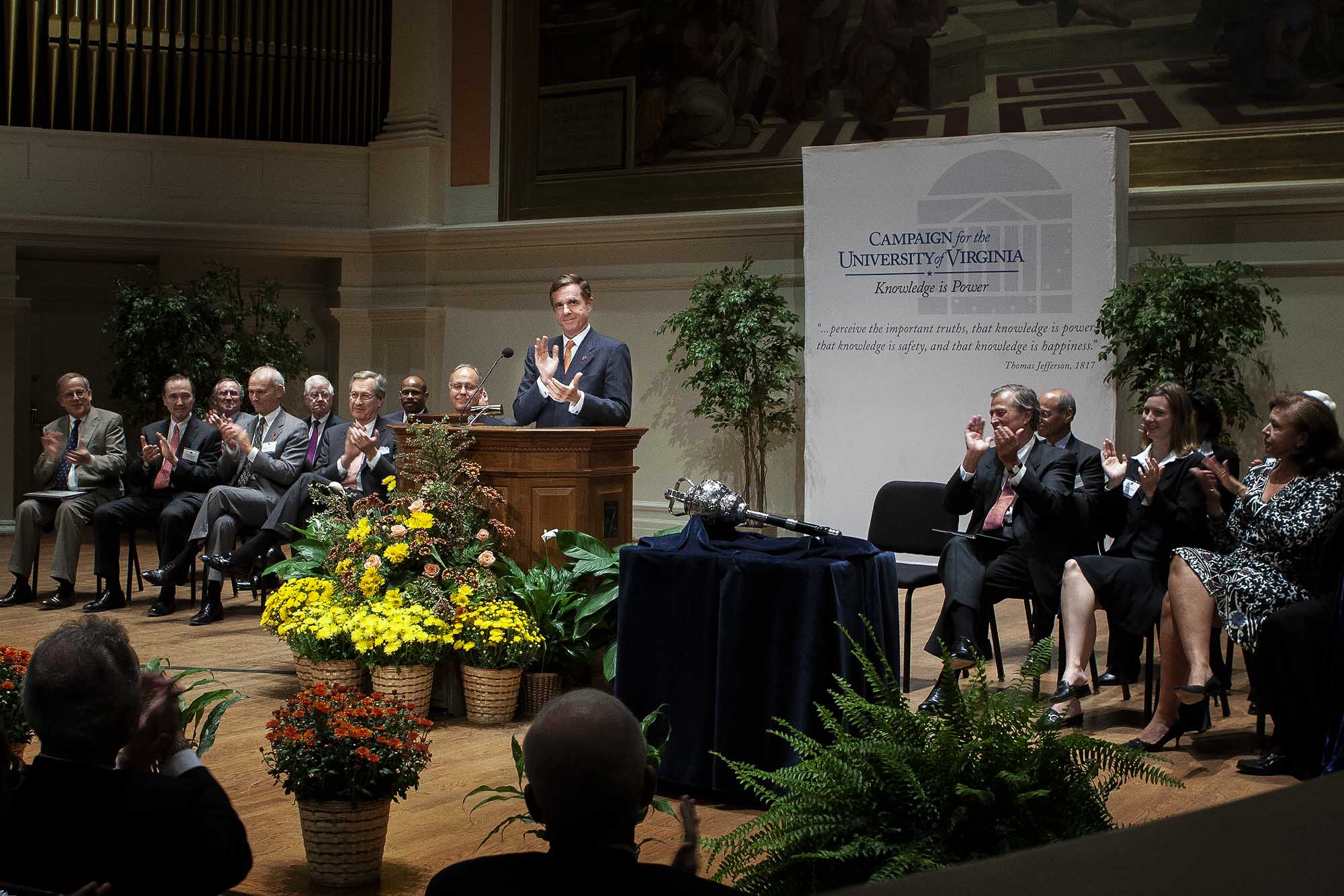 Farrell standing at the podium clapping in front of a group of people