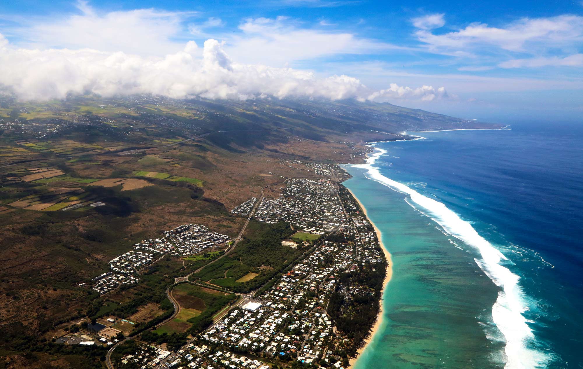 Aerial view of waves crashing on the Reunion Island coast and buildings 