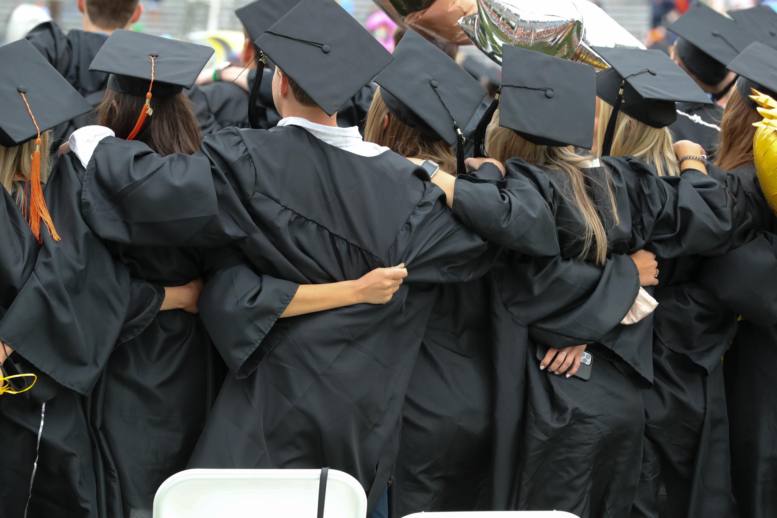 Graduates standing in a line while wrapping their arms around each other 