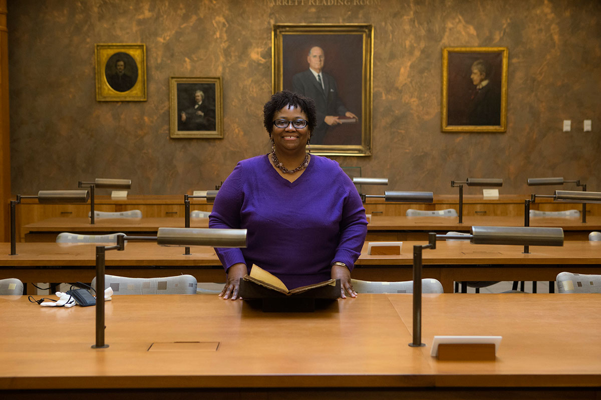 Reference specialist Regina Rush stands with an 1851 Rives family ledger that lists clothing orders for her enslaved great-great-grandparents.