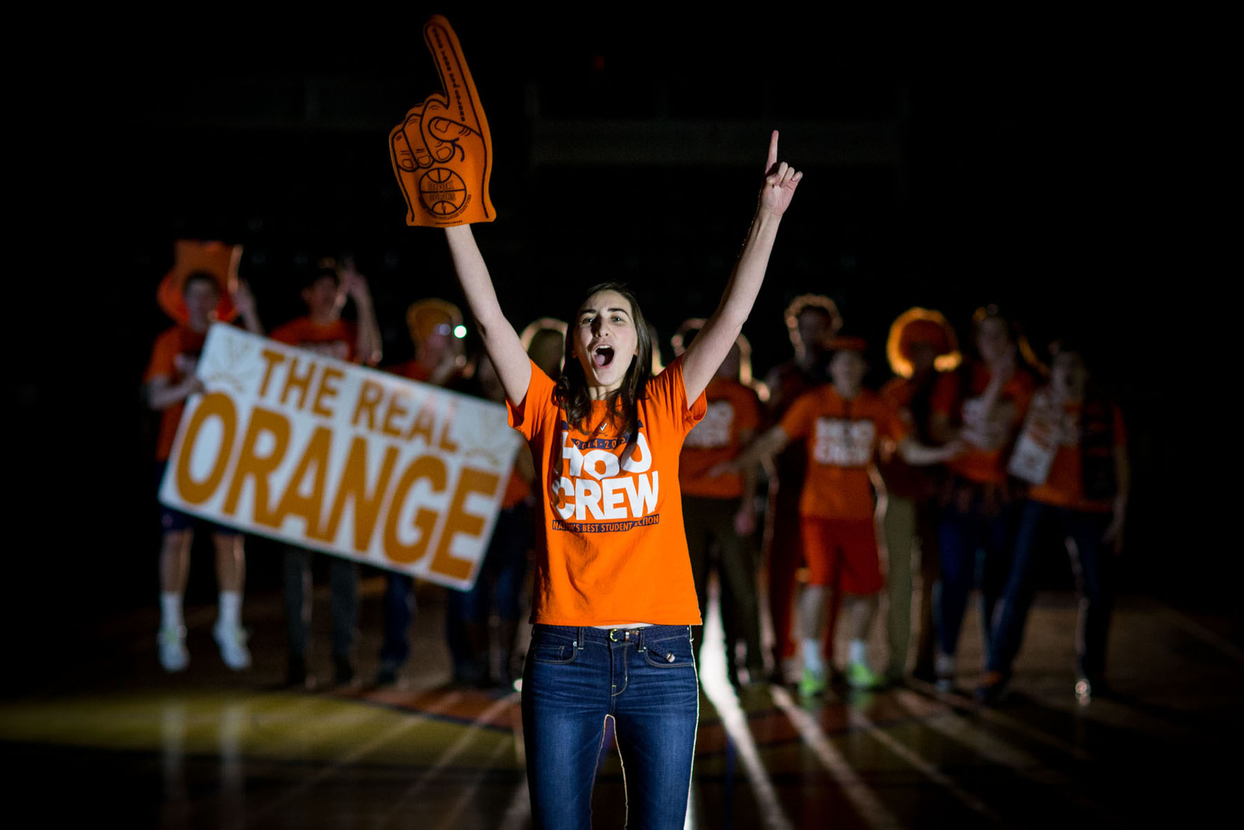 Woman standing in front of a group of students all dressed in UVA gear screaming towards the camera