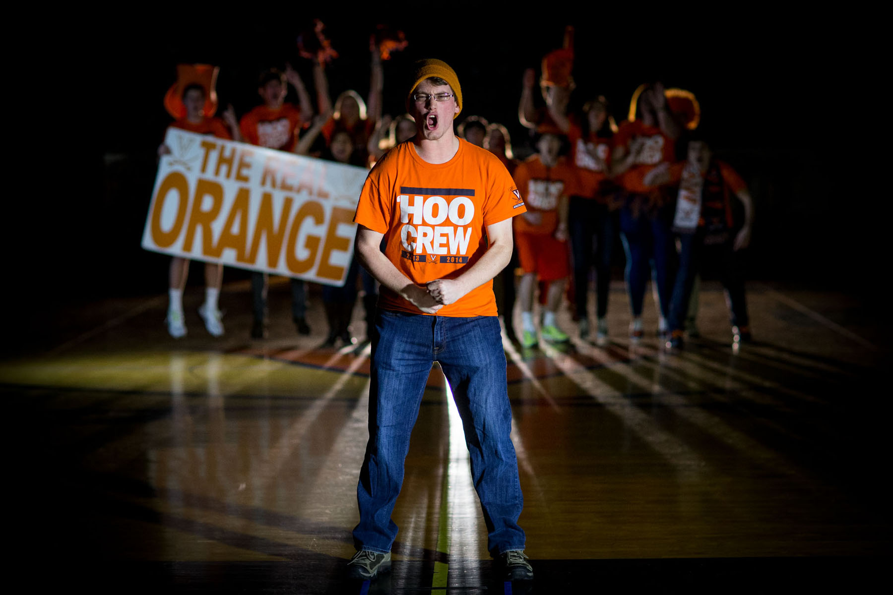 Man standing in front of a group of students all dressed in UVA gear screaming towards the camera